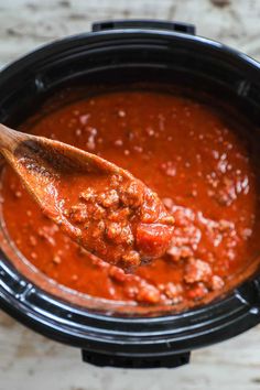 a wooden spoon in a slow cooker filled with chili