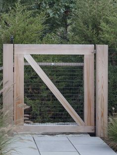 the gate is made out of wood and has a wire mesh design on it, along with tall grass