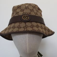 Product Description Crafted From Monogram Canvas, This Bucket Hat Is Completed By A Tonal Leather Trim. Enhanced By The Historic Double G Detail On The Side, Both The Archival References And The Shape Speak To The Vintage Feel That Permeates The House's Design Narrative. Brown Leather Trim Double G Made In Italy Gucci Brown Curved Brim Hat, Gucci Brown Short Brim Hat, Gucci Adjustable Brimmed Hat, Designer Brown Hat With Embroidered Logo, Elegant Gucci Adjustable Hat, Gucci Adjustable Short Brim Hat, Gucci Hat With Adjustable Size And Short Brim, Gucci Designer Wide Brim Hat, Gucci Adjustable Flat Brim Hat