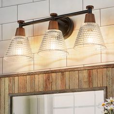 three light bathroom vanity fixture with glass shades on the top and bottom, in an antique finish