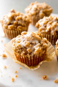 several muffins with white icing and crumbs on them