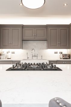 a kitchen with gray cabinets and white counter tops