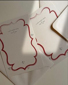 three envelopes with red and white designs are on top of each other next to a card