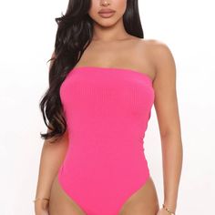 a woman in a pink one piece swimsuit with her hands on her hips, posing for the camera