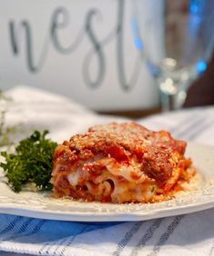 a white plate topped with lasagna covered in sauce and parmesan cheese