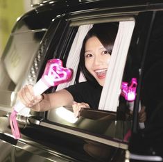 a woman holding a pink hair dryer in her hand while sitting in a car