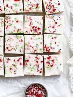 white frosted squares with sprinkles and candy in a bowl next to it