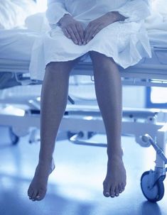 a woman sitting in a hospital bed with her foot up on the edge of the bed