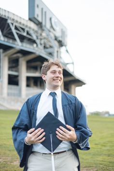 a man in a blue jacket and tie holding a black graduation cap with his hands