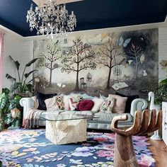 a living room filled with furniture and a large painting on the wall above it's couches