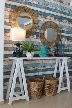 two mirrors on the wall above a table with baskets and plants in front of it