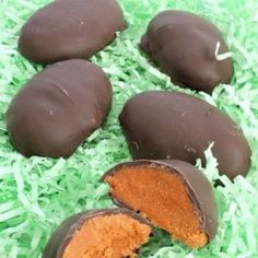 four pieces of chocolate covered candy sitting on top of green shredded paper