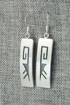 These sterling silver earrings are made by Hopi silversmith Timothy Mowa. The backs are signed and stamped sterling.Length: 1 7/8"Width: 3/8"Free shipping on all orders! We ship with USPS and always include tracking. All orders ship within a day of payment.Returns are accepted up to 30 days after you receive your order. Just send us a message. Our shop offers cash back or store credit. The item must be returned in new condition. Classic Engraved Sterling Silver Earrings, Artisan Sterling Silver Etched Earrings, Traditional Sterling Silver Rectangular Jewelry, Artisan Etched Sterling Silver Earrings, Traditional Rectangular Sterling Silver Jewelry, Silver Symbolic Engraved Earrings, Silver Engraved Symbolic Earrings, Symbolic Engraved Silver Earrings, Etched Sterling Silver Dangle Earrings