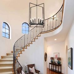 an elegant staircase in a home with wood floors and white walls, surrounded by arched windows