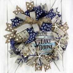 a wreath made out of burlocks and ribbons with the words welcome to lake house on it