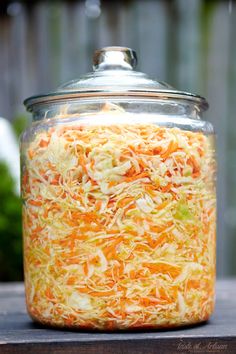 a glass jar filled with shredded carrots on top of a wooden table