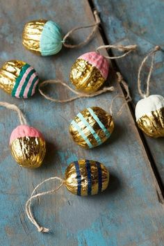 gold and blue striped easter eggs tied to string on a wooden table with twine