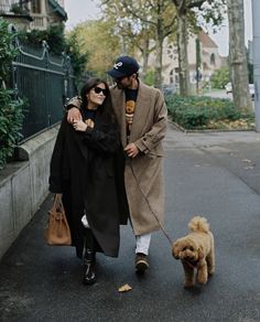 a man and woman walking their dog down the street