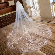 a wedding veil with pink flowers on the bottom is shown in front of a doorway