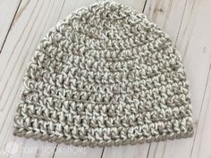 a crocheted beanie sitting on top of a wooden floor next to a pair of scissors