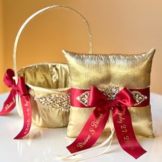 two gold wedding baskets with red ribbons and bows on them, sitting on a table