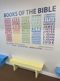 there is a bench in front of a wall with words on it that say books of the bible