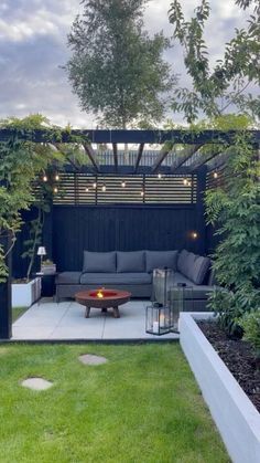 an outdoor living area with couches, tables and lights in the middle of it