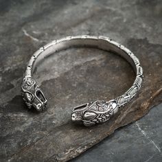 Our Stainless Steel Dragon Head Braided Torc Bracelet is a lovely example of Celtic design and craftsmanship: a chunky solid stainless steel bracelet with intricate Celtic beaded knotwork and topped with double dragon heads. The bracelet has an internal diameter of approximately 2.75 inches (7 cm) and can be adjusted by squeezing the clasp together or pulling it apart. PLEASE NOTE - THIS IS A SOLID BRACELET! YOU WILL NEED SOME FORCE TO OPEN AND CLOSE THE HEADS TO FIT. BEST LEFT ON ONCE ADJUSTED. Braid Beads, Beard Rings, Viking Arm Rings, Head Braid, Celtic Braid, Steel Dragon, Dragon Heads, Viking Jewellery, Norse Jewelry