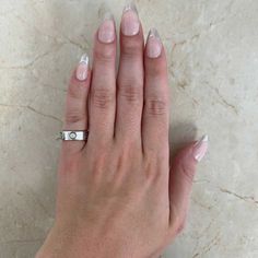 a woman's hand with white nail polish and a ring on her left hand