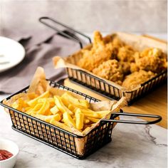 two baskets filled with food sitting on top of a counter next to another basket full of fries