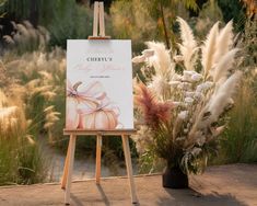 an easel with a sign in front of some plants