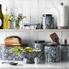 the kitchen counter is covered with blue and white dishes, utensils, and bread