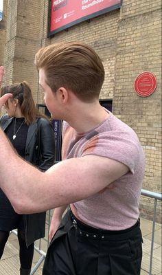 a man is holding his cell phone up to his ear as he looks at it