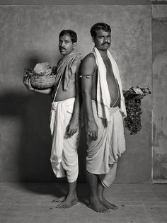 two men standing next to each other in front of a wall