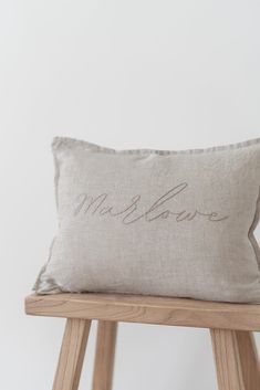 a pillow with the word love on it sitting on top of a wooden stool in front of a white wall