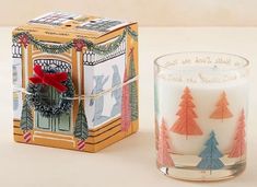 a candle with a christmas decoration next to a box