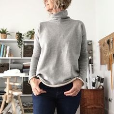 a woman standing in front of a white wall with her hands on her hips and looking off to the side