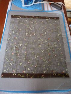 a piece of cloth with flowers on it sitting on top of a table next to an ironing board