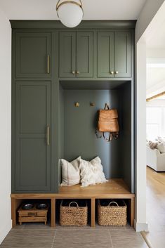 a wooden bench sitting under a light fixture in a room with green cabinets and drawers