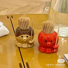 two ceramic toothbrush holders sitting on top of a table next to a glass vase