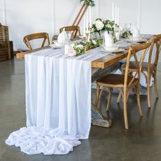 the table is set with white linens, flowers and candles for an elegant dinner