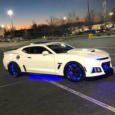 a white sports car with blue lights on it's side in a parking lot