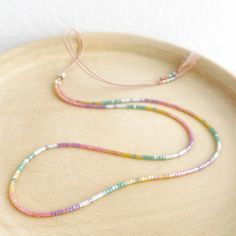 Our Shimmer Rainbow necklace is made to catch the light when you move with rainbow coloured glass beads and silver sliding clasp to adjust length.  The silk cord is a pale pink colour and the beads are high quality glass beads in pink, peach, yellow, green, pale blue and lilac. This delicate necklace measures 26in at its longest (pulls on over the head) and has a silver sliding bead so you can shorten it to 16in. Comes displayed in one of our pretty gift boxes, so fantastic as a present for a friend or to yourself! Check out the matching bracelet https://www.etsy.com/uk/listing/1279384412/shimmer-rainbow-bracelet-delicate-beaded Shipping Uk: 2-3 days - Royal Mail 48hr tracked International standard delivery: 6- 14 days (delays can occur especially in busy periods) Please be aware that stan Multicolor Adjustable Lariat Necklace, Adjustable Single Strand Pink Beaded Necklace, Rainbow Round Bead Adjustable Necklace, Adjustable Rainbow Round Bead Necklaces, Iridescent Adjustable Round Bead Necklaces, Adjustable Pastel Beaded Jewelry, Adjustable Rainbow Necklace With Colorful Beads, Iridescent Adjustable Necklace With Round Beads, Adjustable Pastel Beaded Necklaces