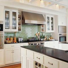 a large kitchen with white cabinets and black counter tops, along with stainless steel appliances