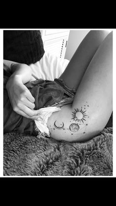 a woman laying on top of a bed with her legs crossed and sun and moon tattoos