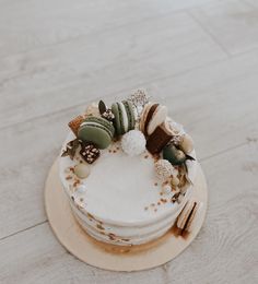 a close up of a cake on a wooden table with white frosting and decorations