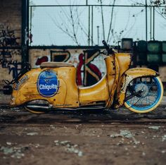 an old yellow scooter parked in front of a building