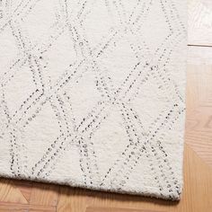 a white rug with an intricate design on the top and bottom, sitting on a wooden floor