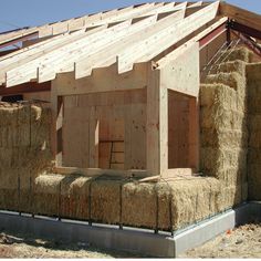 straw bales stacked on top of each other in front of a house under construction