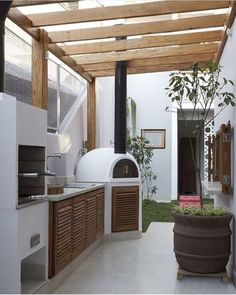 an outdoor kitchen is shown with wood and white walls, along with potted plants